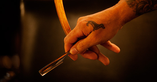 Close up photograph of a man's hand holding a straight razor